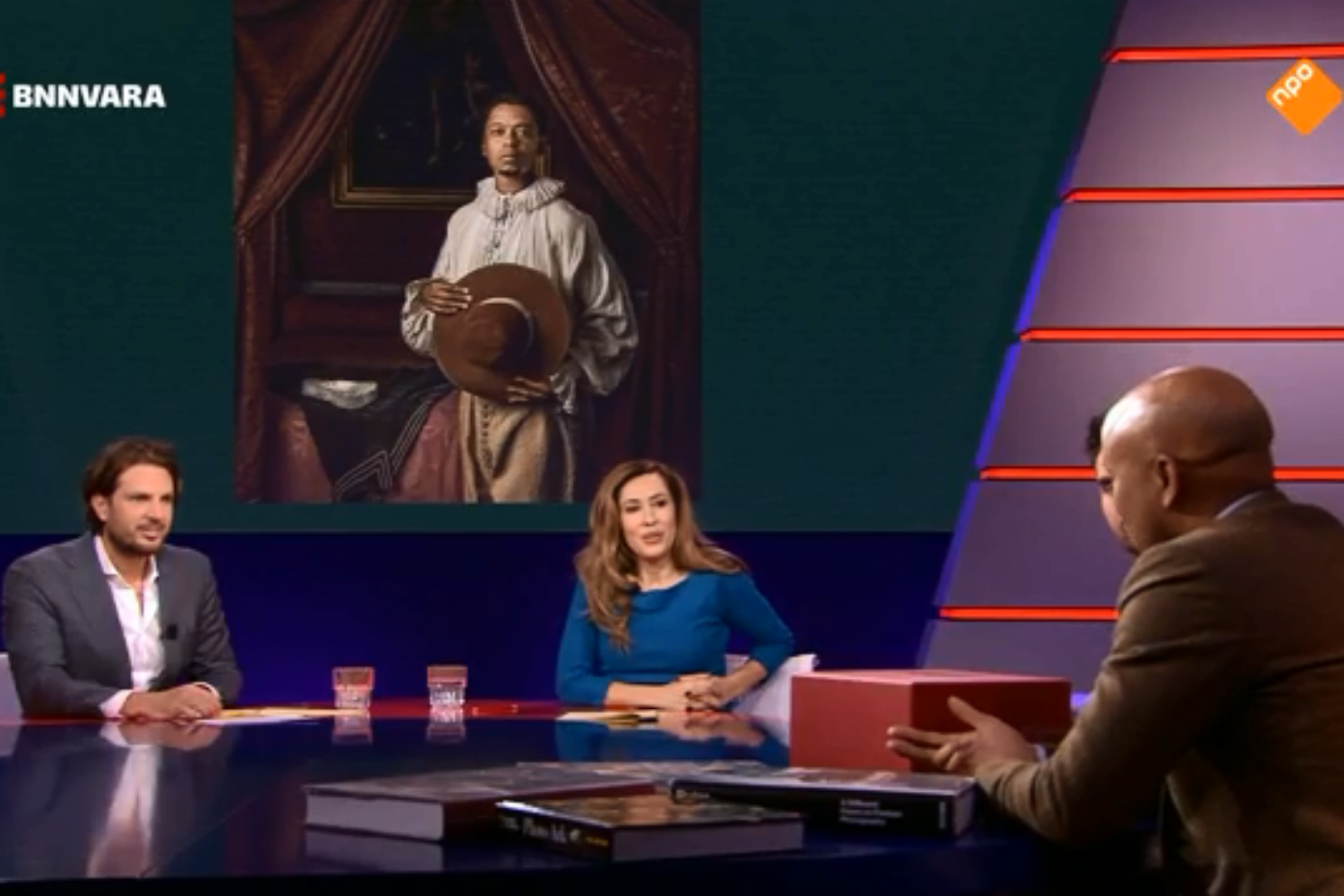 Humberto Tan aan tafel bij De Vooravond met in achtergrond de foto die hij nam voor de tentoonstelling Hollandse Meesters Her-Zien welke afgedrukt is in The New York Times